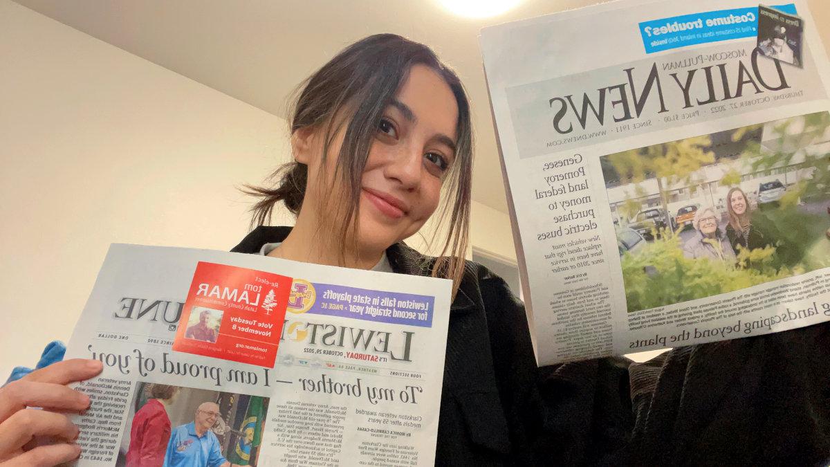 Photo of woman holding two newspapers.